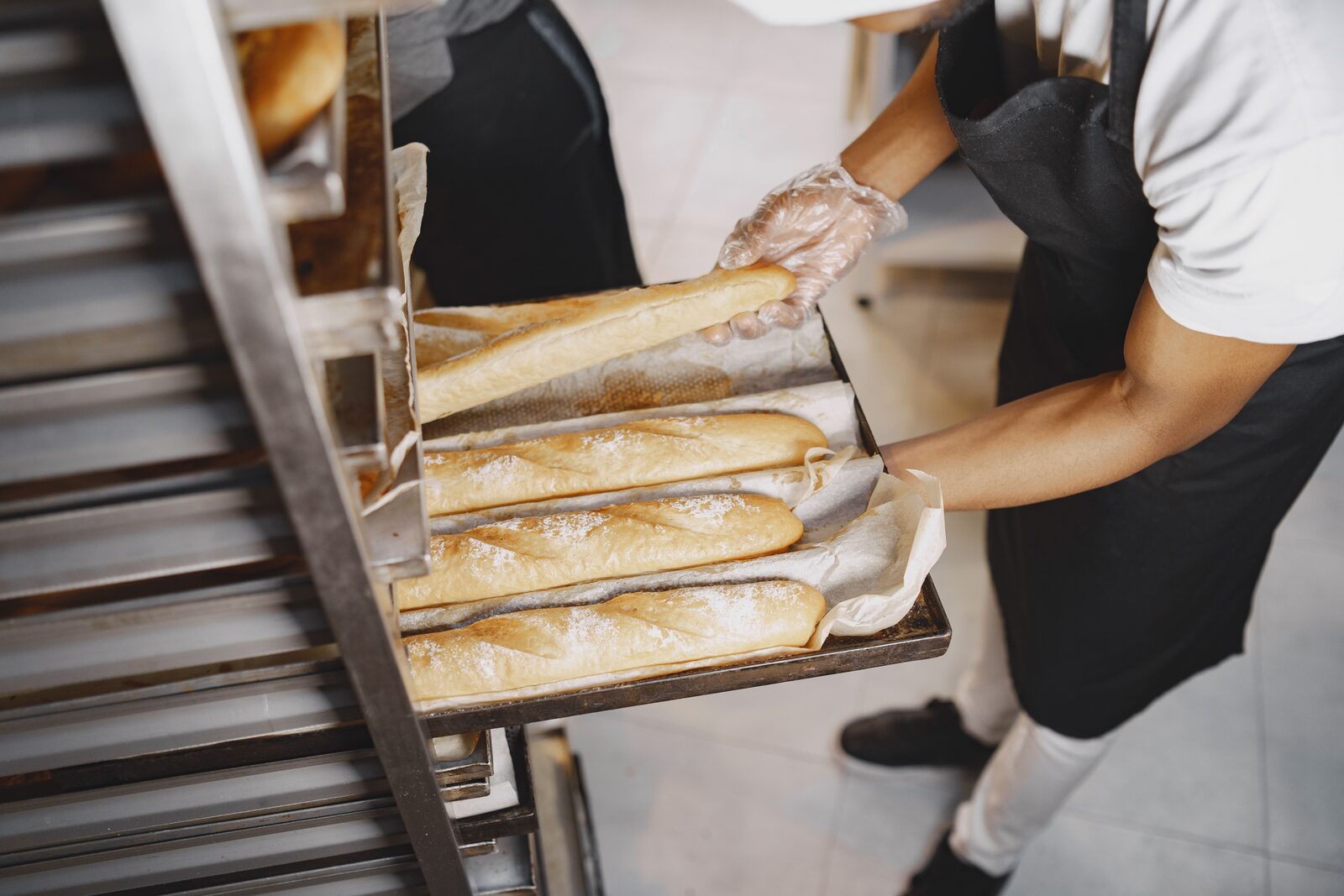 Boulanger sortant une plaque de baguettes du four