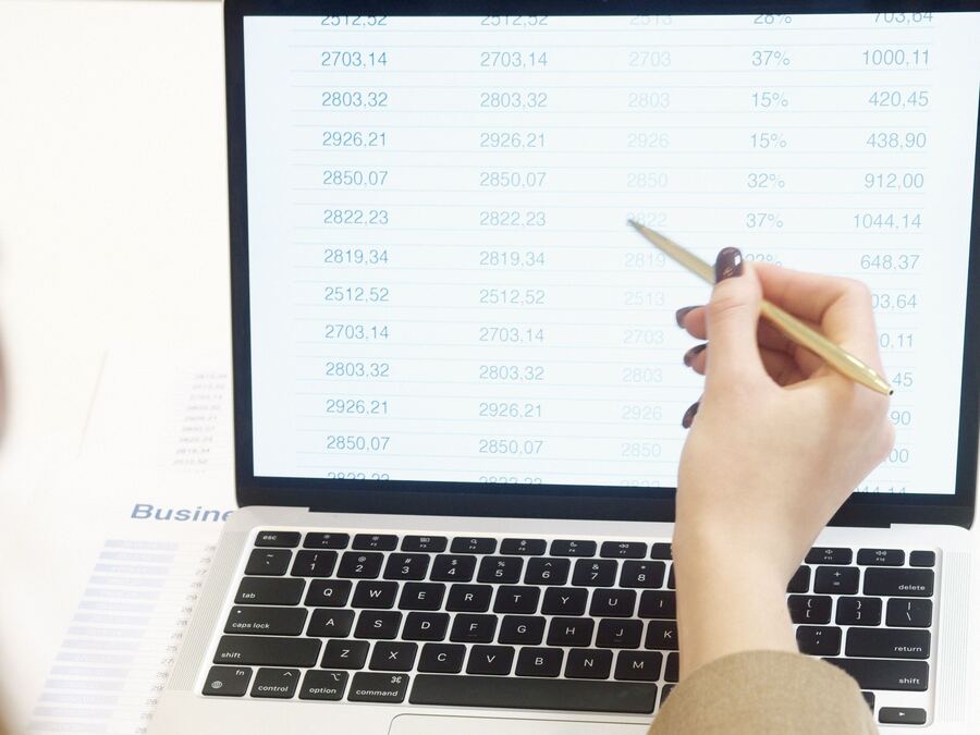 Tableur affiché sur un ordinateur portable, main tenant un stylo